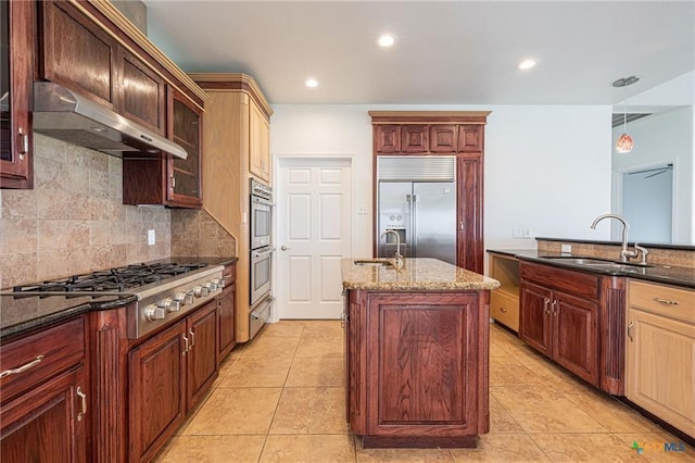 kitchen with appliances with stainless steel finishes, a sink, under cabinet range hood, a kitchen island with sink, and recessed lighting