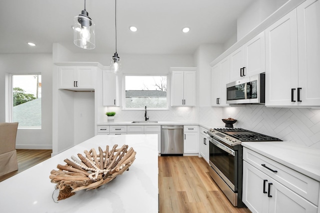1218 English St, Houston, TX 77009 - kitchen featuring stainless steel appliances, a sink, light wood-style flooring, light countertops, and white cabinets
