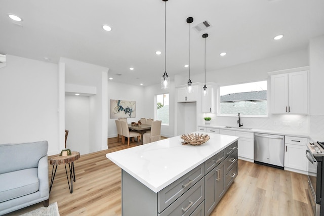 1218 English St, Houston, TX 77009 - kitchen featuring appliances with stainless steel finishes, gray cabinetry, light countertops, white cabinets, and a sink