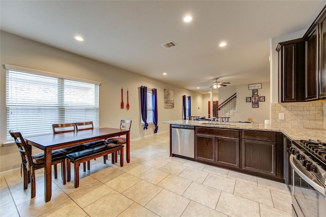 kitchen featuring appliances with stainless steel finishes, dark brown cabinetry, recessed lighting, a peninsula, and light stone countertops