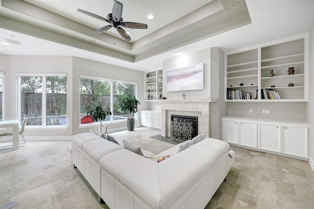 910 Peachwood Bend Dr, Houston, TX 77077 - living room featuring stone tile flooring, a tray ceiling, built in features, and a premium fireplace