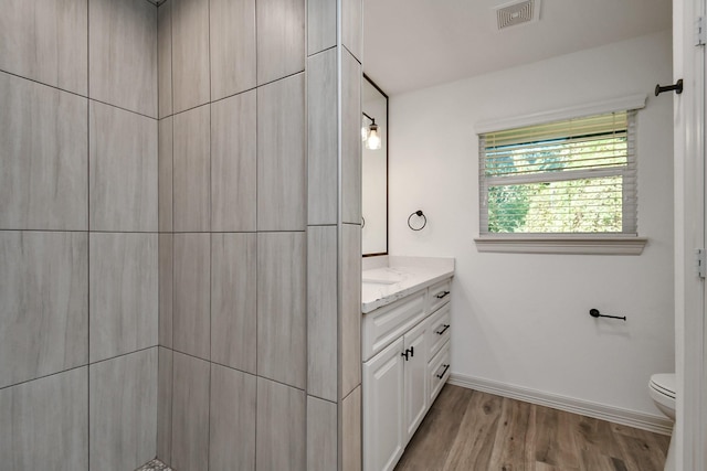 1805 E Ave, Katy, TX 77493 - bathroom with vanity, baseboards, toilet, wood finished floors, and tiled shower