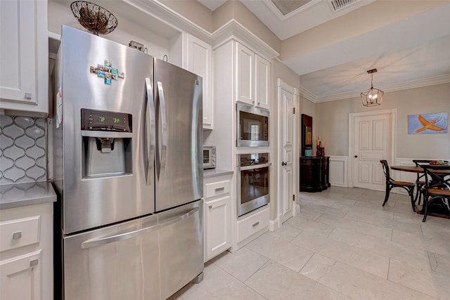 kitchen featuring stainless steel appliances, light countertops, white cabinetry, hanging light fixtures, and ornamental molding