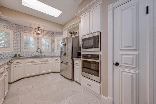kitchen with stainless steel appliances, a sink, light countertops, open shelves, and white cabinets