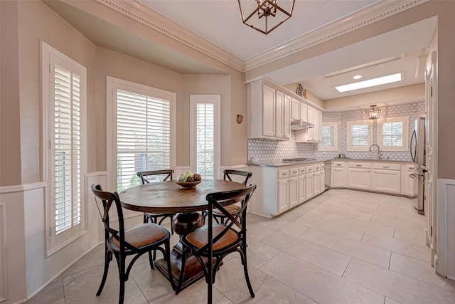 dining space with ornamental molding, wainscoting, and light tile patterned floors