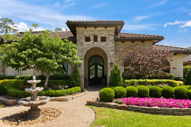 38 Post Shadow Estate Dr, Spring, TX 77389 - view of exterior entry featuring french doors, a tiled roof, stone siding, and stucco siding