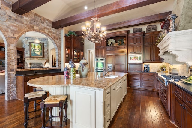 38 Post Shadow Estate Dr, Spring, TX 77389 - kitchen with built in appliances, dark wood-type flooring, a sink, beam ceiling, and light stone countertops