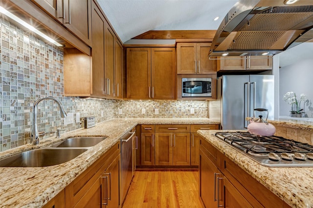 1309 Nashua St Unit A, Houston, TX 77008 - kitchen with stainless steel appliances, wall chimney range hood, a sink, brown cabinets, and light wood-style floors