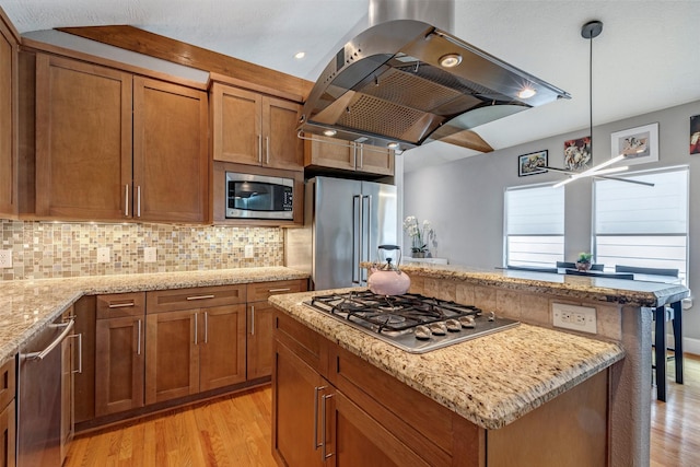 1309 Nashua St Unit A, Houston, TX 77008 - kitchen featuring stainless steel appliances, island exhaust hood, light wood finished floors, brown cabinetry, and backsplash
