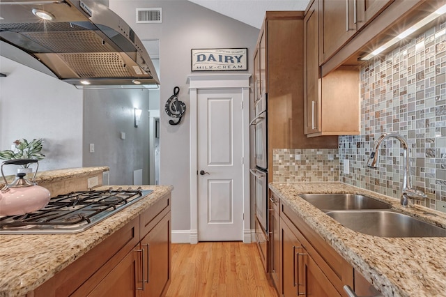 1309 Nashua St Unit A, Houston, TX 77008 - kitchen with appliances with stainless steel finishes, a sink, ventilation hood, brown cabinets, and light wood-style flooring