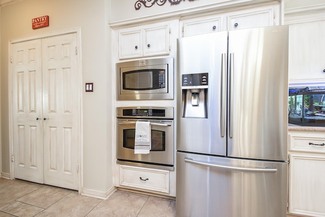 14 Wickham Ct, Sugar Land, TX 77479 - kitchen with stainless steel appliances, light tile patterned floors, baseboards, light countertops, and white cabinets