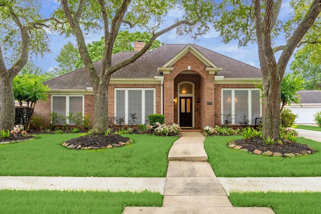 traditional-style house with a chimney, brick siding, and a front yard