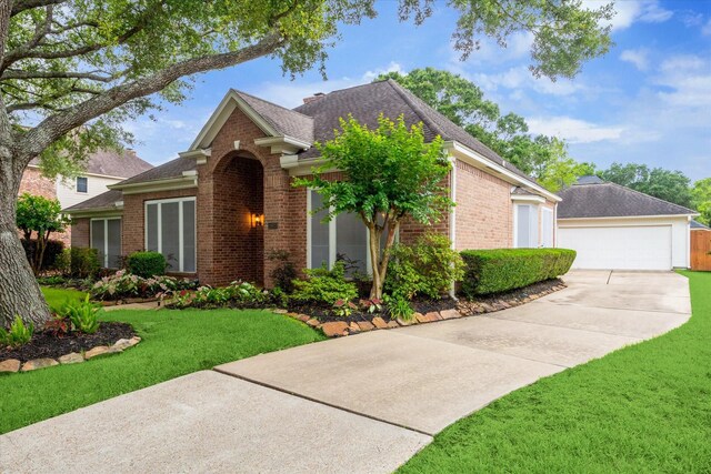 view of front of home with brick siding, a shingled roof, a front lawn, and a garage