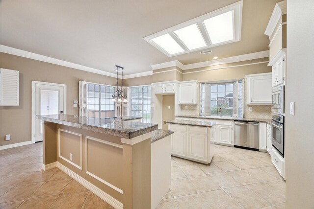 kitchen with stainless steel appliances, a kitchen island, light tile patterned floors, crown molding, and backsplash