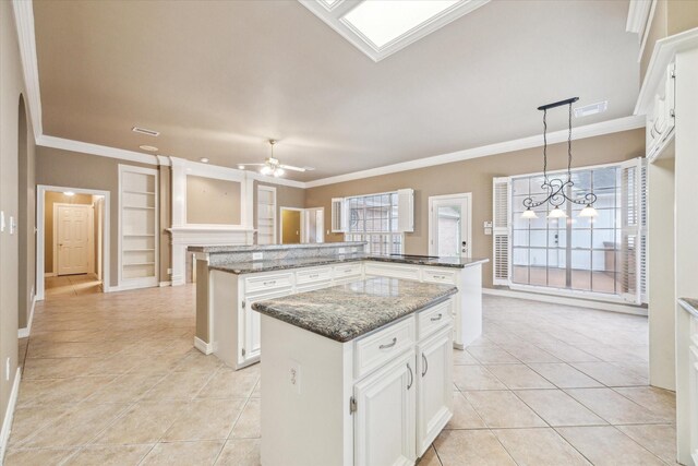 kitchen featuring a kitchen island, light tile patterned flooring, built in shelves, crown molding, and ceiling fan
