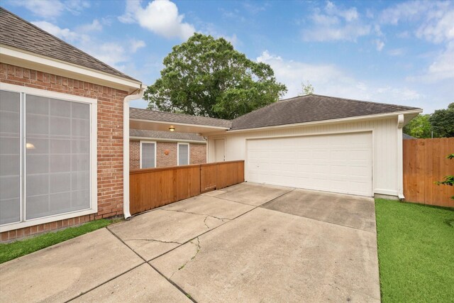 view of front of home with fence, a garage, driveway, brick siding, and roof with shingles