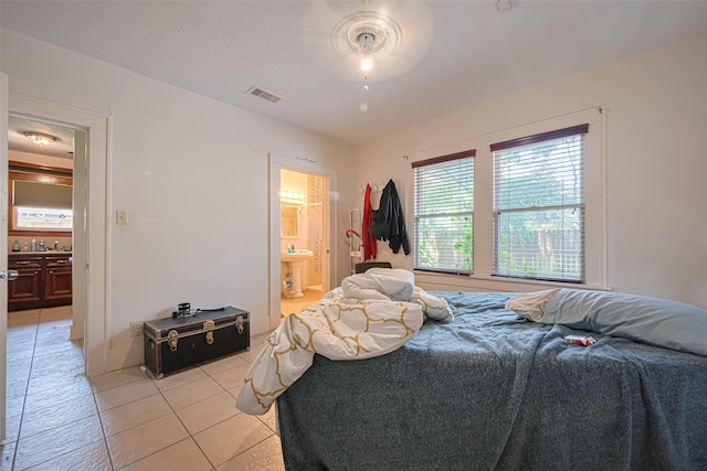 bedroom featuring light tile patterned flooring, ensuite bath, and ceiling fan