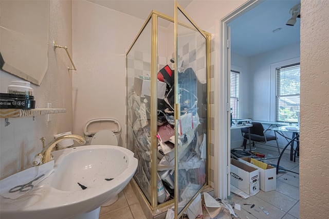 full bath featuring tile patterned flooring, a sink, a shower stall, and a textured wall