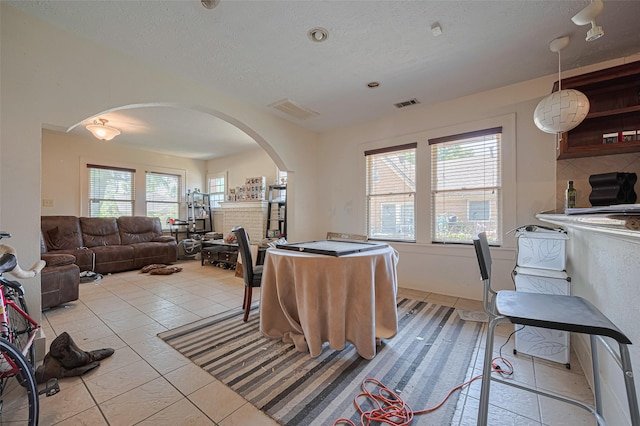 living room featuring arched walkways, a textured ceiling, and light tile patterned floors
