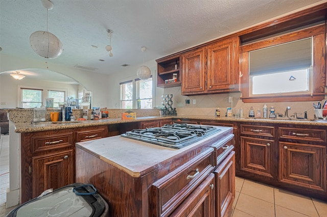 kitchen featuring gas stovetop, a sink, healthy amount of natural light, open shelves, and a textured ceiling