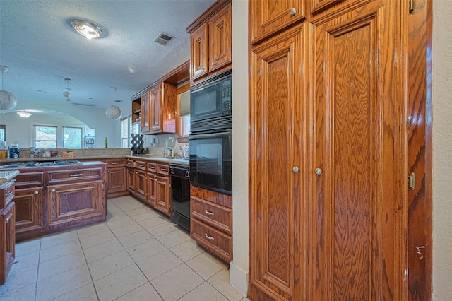 kitchen with black appliances, a textured ceiling, light tile patterned flooring, brown cabinets, and arched walkways