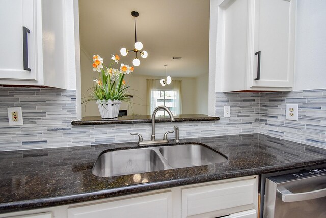 kitchen featuring a sink, dishwasher, tasteful backsplash, white cabinetry, and dark stone counters