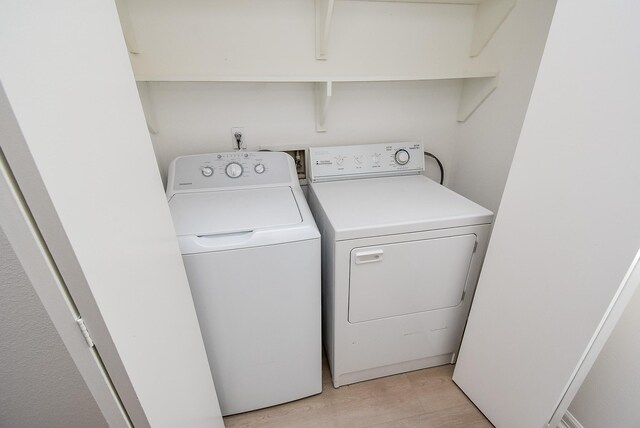 laundry area with washer and dryer and light wood-style floors