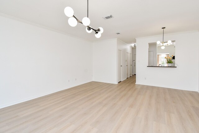 unfurnished living room featuring a chandelier, ornamental molding, light wood finished floors, and baseboards