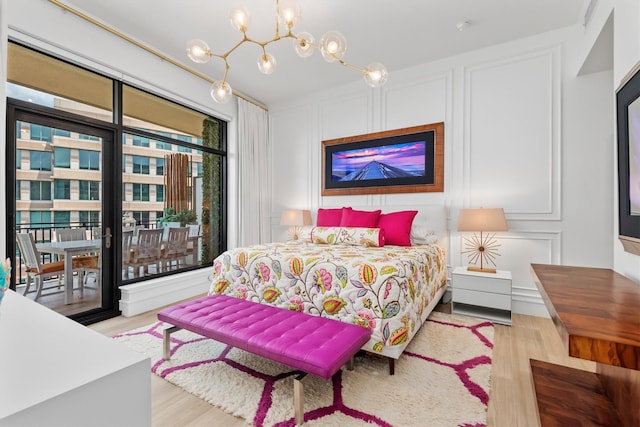 1 Waterway Ct Unit 4B, The Woodlands, TX 77380 - bedroom with a decorative wall, wood finished floors, access to exterior, and a chandelier