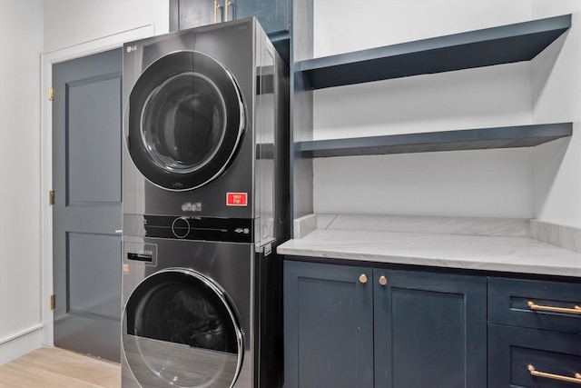 1 Waterway Ct Unit 4B, The Woodlands, TX 77380 - laundry room featuring stacked washing machine and dryer, cabinet space, and wood finished floors