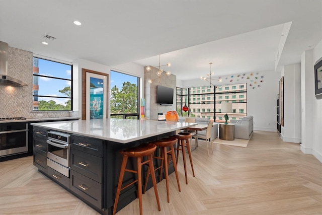 1 Waterway Ct Unit 4B, The Woodlands, TX 77380 - kitchen featuring stainless steel appliances, dark cabinets, tasteful backsplash, a spacious island, and light stone countertops