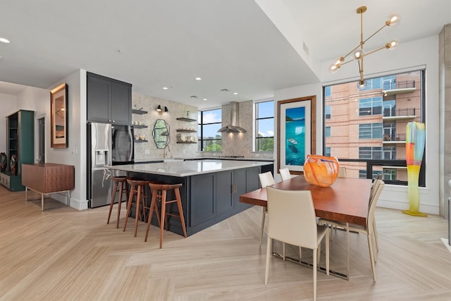1 Waterway Ct Unit 4B, The Woodlands, TX 77380 - kitchen featuring stainless steel fridge with ice dispenser, open shelves, wall chimney exhaust hood, decorative backsplash, and a kitchen island