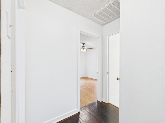 hall featuring dark wood-style floors, baseboards, and a textured ceiling