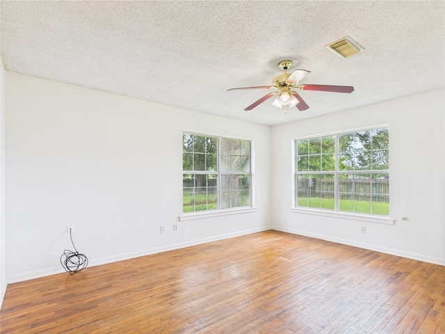 spare room with ceiling fan, wood-type flooring, baseboards, and a textured ceiling