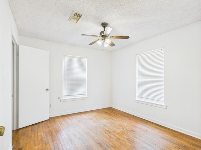 unfurnished room with wood-type flooring, a ceiling fan, baseboards, and a textured ceiling