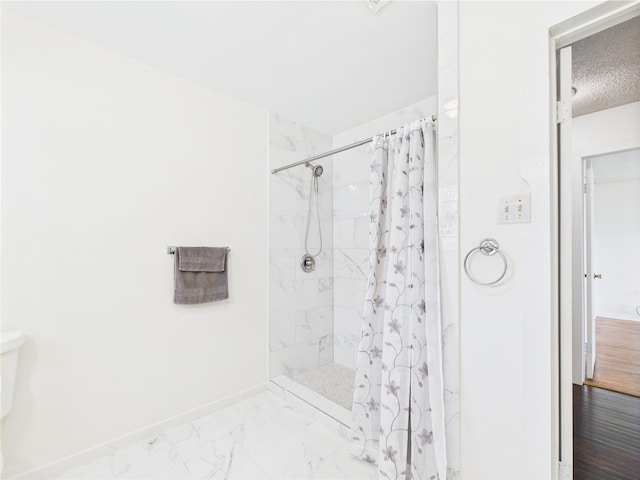 bathroom featuring baseboards, tiled shower, marble finish floors, a textured ceiling, and toilet