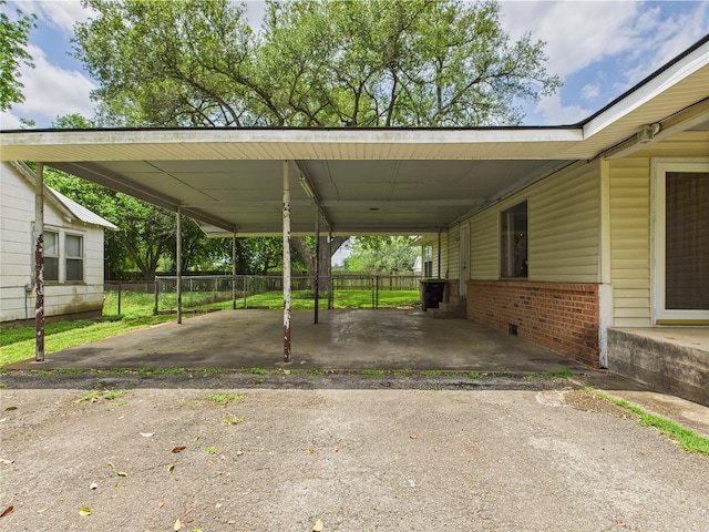 view of vehicle parking with fence, a carport, and driveway