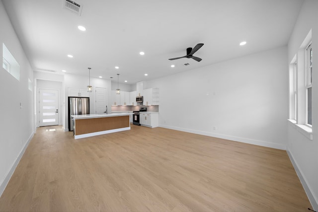1307 Amundsen St N, Houston, TX 77009 - unfurnished living room with a ceiling fan, light wood-style flooring, recessed lighting, a sink, and baseboards