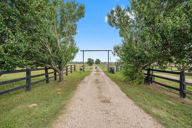 34334 Howell Rd, Waller, TX 77484 - view of dirt / gravel road with a gate, a view of countryside, and a gated entry