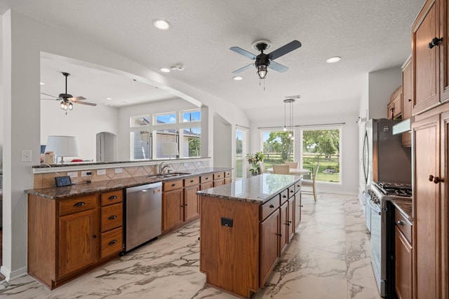 34334 Howell Rd, Waller, TX 77484 - kitchen with appliances with stainless steel finishes, ceiling fan, a sink, brown cabinets, and light marble finish floors