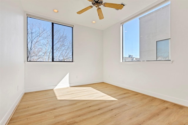 spare room featuring plenty of natural light, wood finished floors, baseboards, and recessed lighting