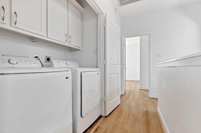 laundry room with cabinet space, light wood finished floors, independent washer and dryer, and baseboards