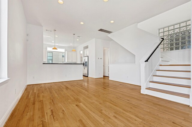 unfurnished living room featuring light wood-type flooring, recessed lighting, stairway, and baseboards