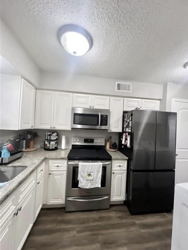 2112 Greenbriar Colony Dr, Houston, TX 77032 - kitchen featuring stainless steel appliances, a textured ceiling, white cabinetry, and dark wood-type flooring