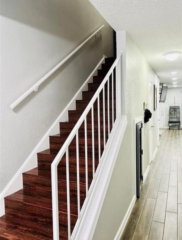 2112 Greenbriar Colony Dr, Houston, TX 77032 - stairs featuring a textured ceiling, wood finished floors, and baseboards