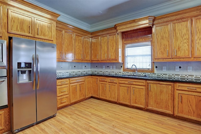2709 Blodgett St, Houston, TX 77004 - kitchen featuring appliances with stainless steel finishes, crown molding, light wood-style floors, decorative backsplash, and dark countertops