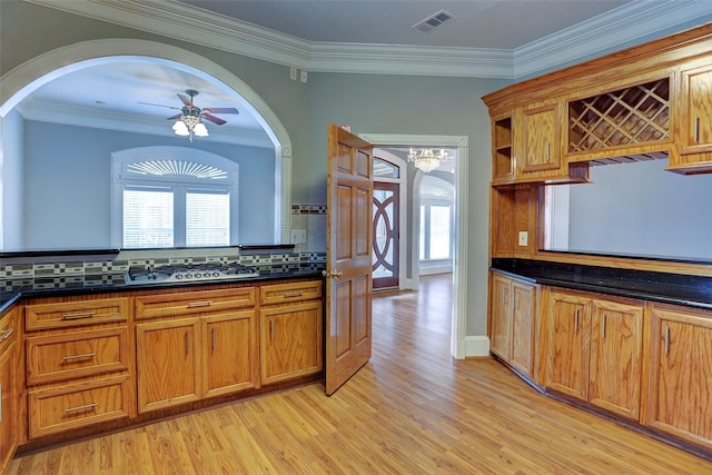 2709 Blodgett St, Houston, TX 77004 - kitchen featuring light wood-type flooring, ceiling fan, arched walkways, dark countertops, and brown cabinets