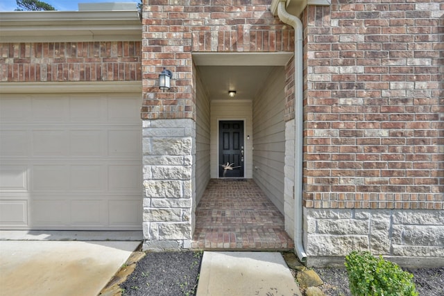 doorway to property featuring brick siding and a garage