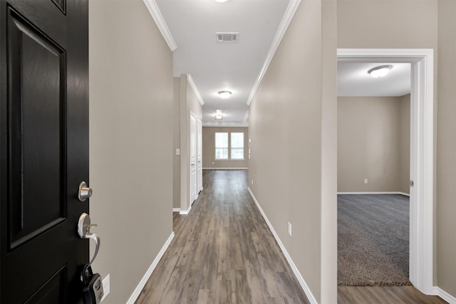 hallway featuring crown molding, wood finished floors, and baseboards