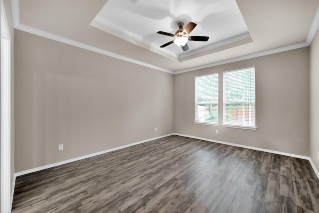 unfurnished room with a raised ceiling, dark wood-style flooring, a ceiling fan, ornamental molding, and baseboards